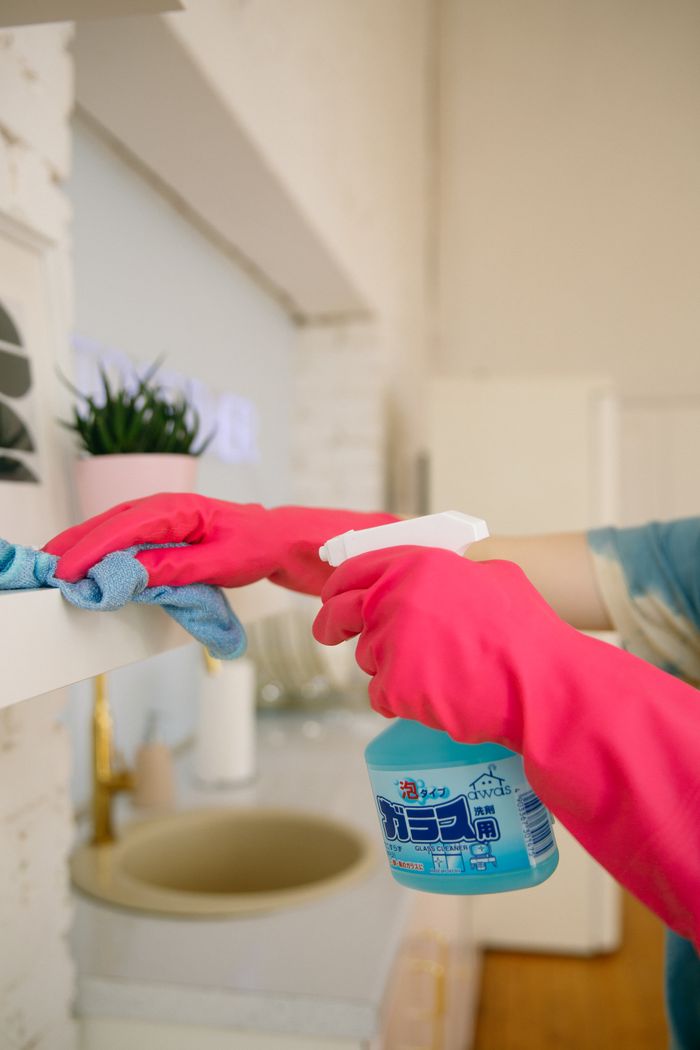 gallery-3 Une personne utilise un vaporisateur et un chiffon pour nettoyer une étagère de cuisine, en veillant à l’hygiène et à la propreté.